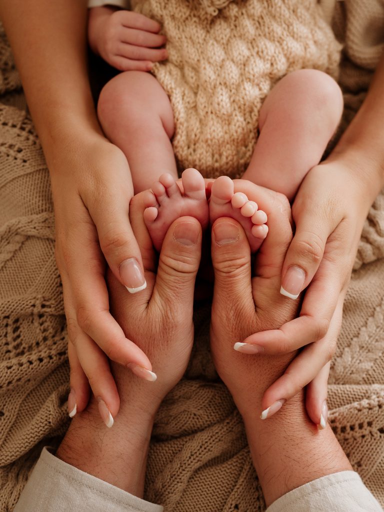 Tiny newborn baby feet held in their parents' hands