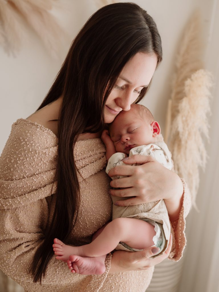 Mum cuddling her sleeping baby during a newborn photography session in Perth