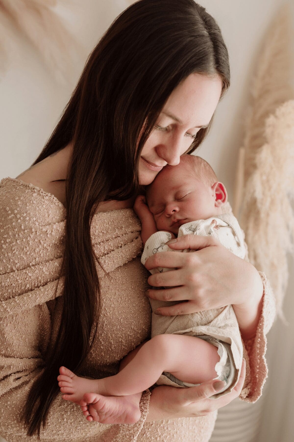 Mum cuddling her sleeping baby during a newborn photography session in Perth