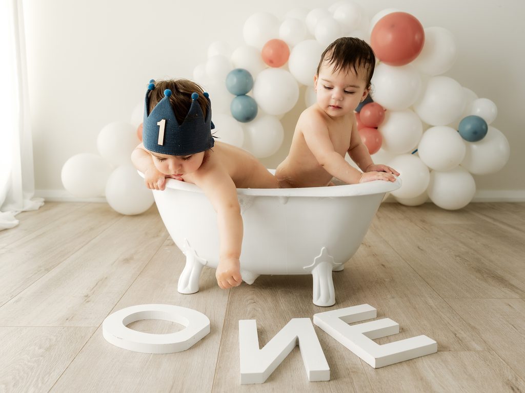 One-year-old baby enjoying a bath splash after a cake smash session