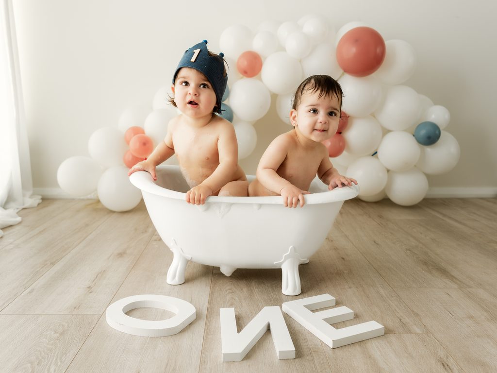 Smiling baby enjoying a bath splash after a cake smash photoshoot at Four O Photography.
